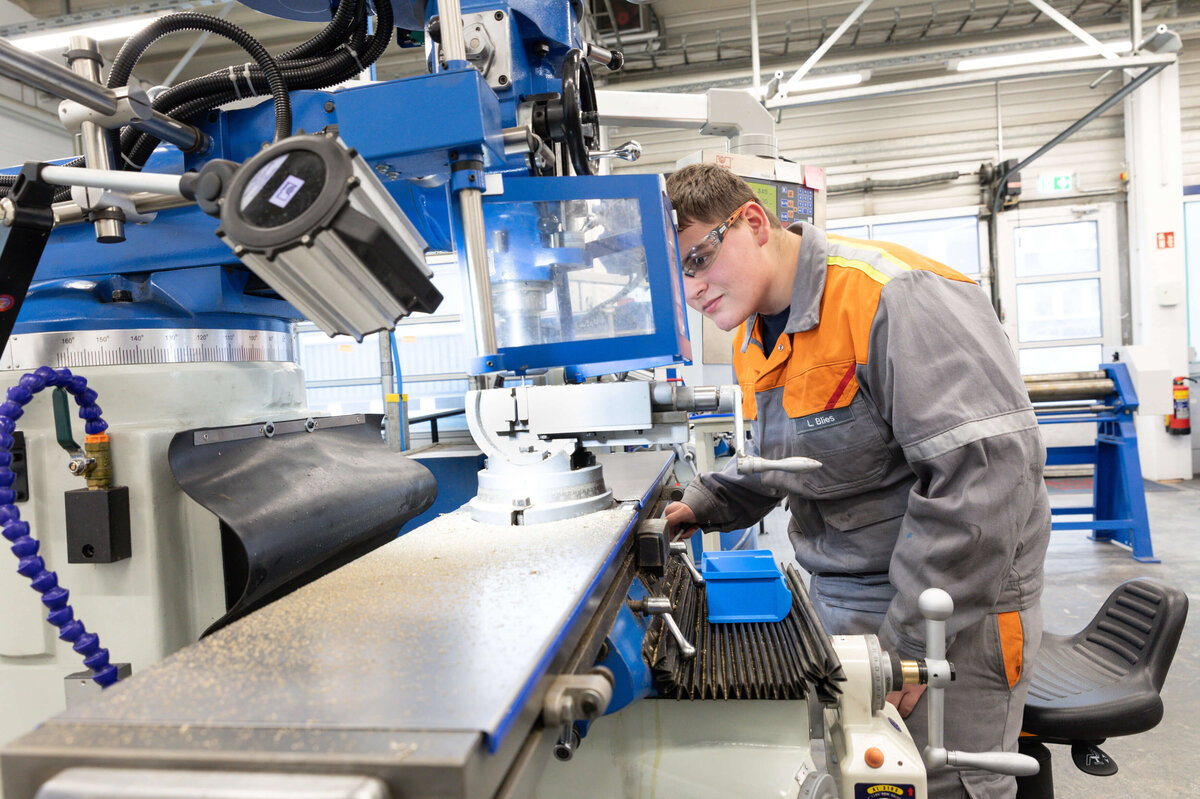Learning at the machine: An apprentice works intently at a milling machine – safety and precision are paramount.